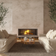 Salón con chimenea encendida, sofás de lino enfrentados, olivos en maceta y mesa de centro de tronco de madera