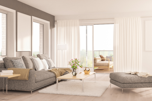 Salón de estilo nórdico con sofá gris, mesa de centro de madera clara, alfombra blanca y cortinas de lino